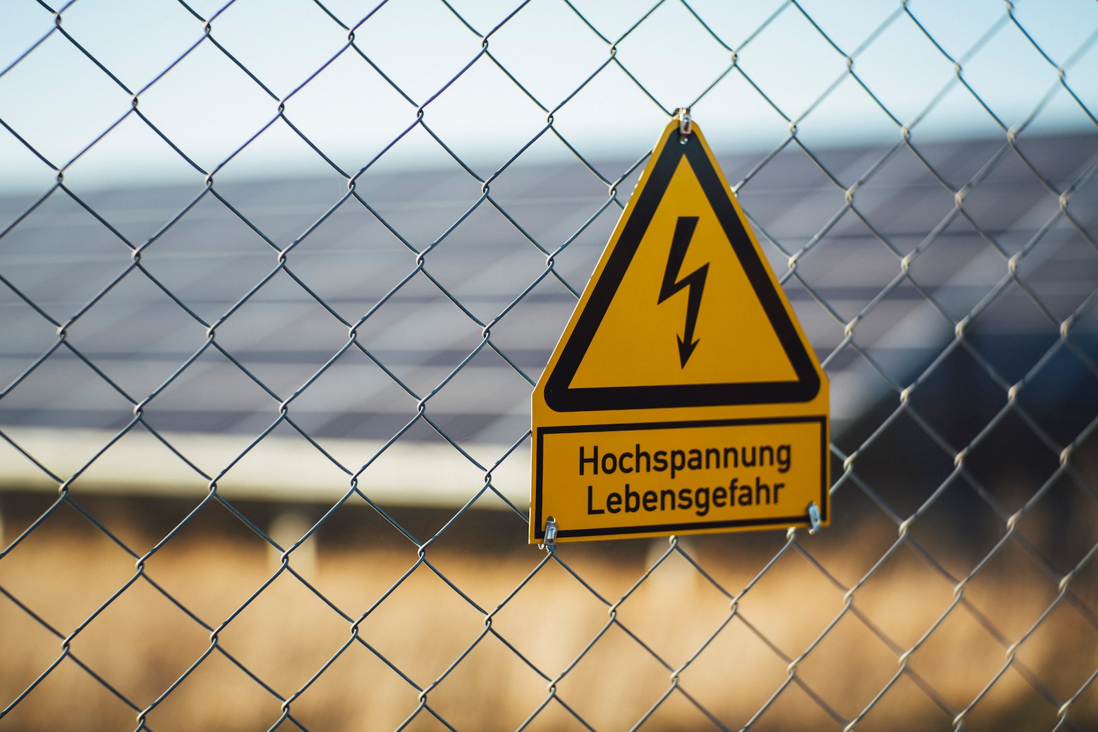 selective focus photography of danger high voltage signage on chain-link fence